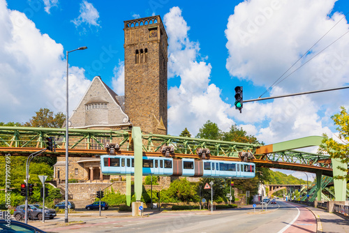 Schwebebahn Train Passing a Church at a junction in Wuppertal, Germany. The Schwebebahn is the oldest electric elevated railway with hanging cars in the world. photo