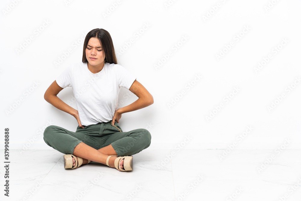Teenager girl sitting on the floor suffering from backache for having made an effort Teenager girl sitting on the floor suffering from backache for having made an effort