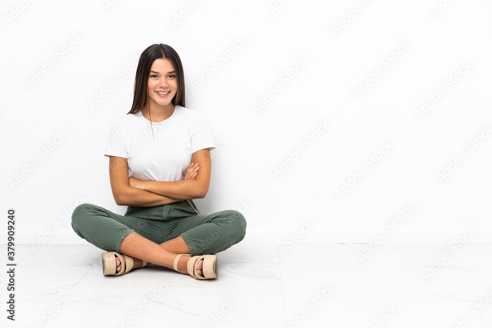 Teenager girl sitting on the floor with arms crossed and looking forward Teenager girl sitting on the floor with arms crossed and looking forward