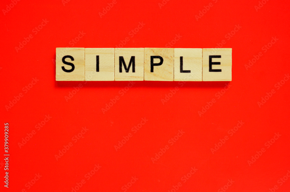 Word simple. Wooden blocks with lettering on top of red background. Top view of wooden blocks with letters on red surface Word simple. Wooden blocks with lettering on top of red background. Top view of wooden blocks with letters on red surface
