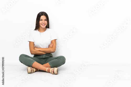 Teenager girl sitting on the floor with arms crossed and looking forward