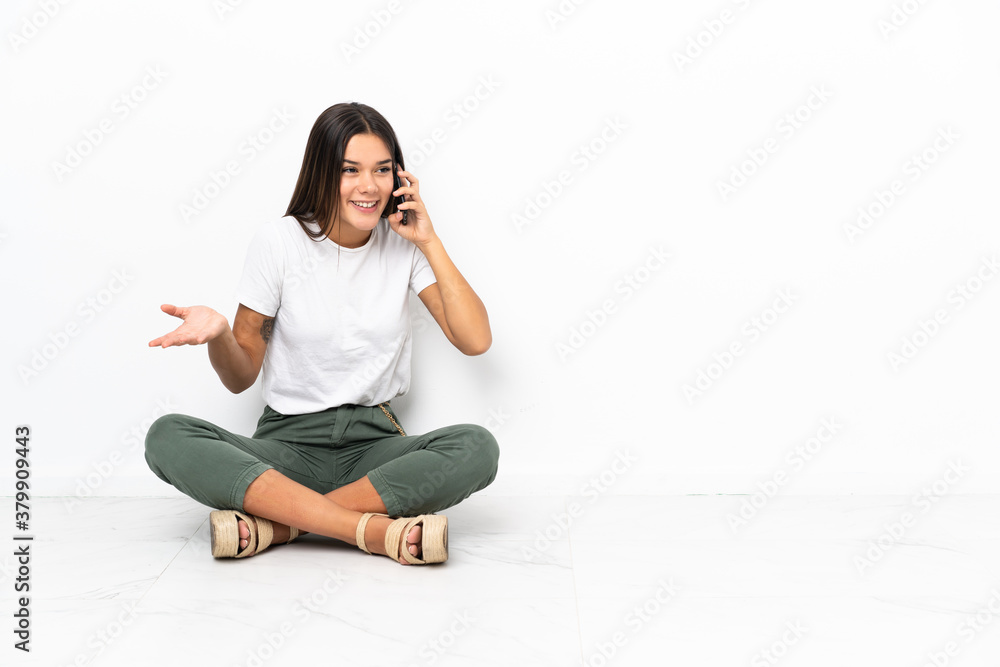 Teenager girl sitting on the floor keeping a conversation with the mobile phone with someone Teenager girl sitting on the floor keeping a conversation with the mobile phone with someone