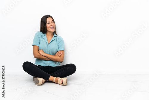 Teenager girl sitting on the floor happy and smiling