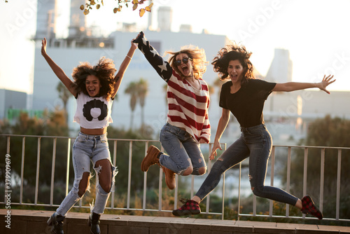 Cheerful girlfriends jumping against city buildings. photo