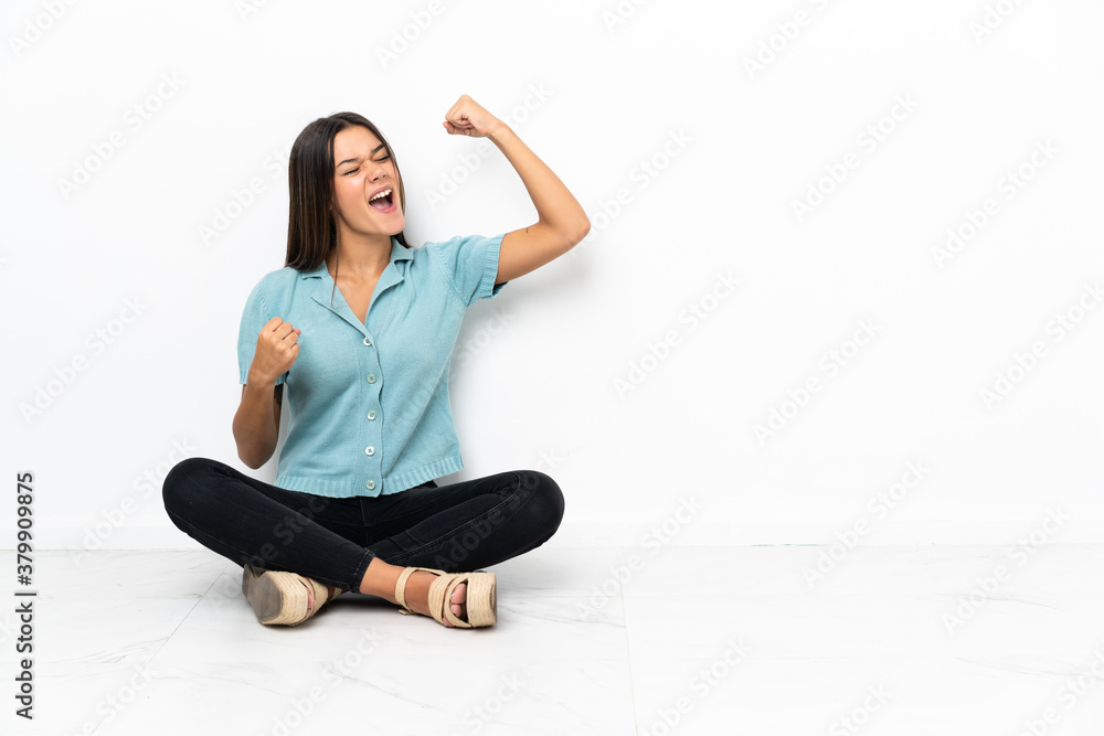 Teenager girl sitting on the floor celebrating a victory Teenager girl sitting on the floor celebrating a victory