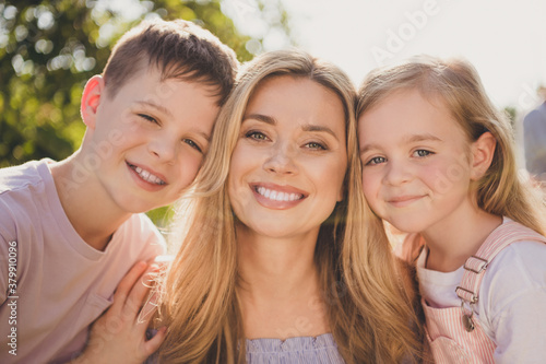 Closeup portrait photo of full big family three people caring mother two small kids beaming shiny smile cudlle waiting enjoy last sunny summer days green grass garden park backyard outdoors