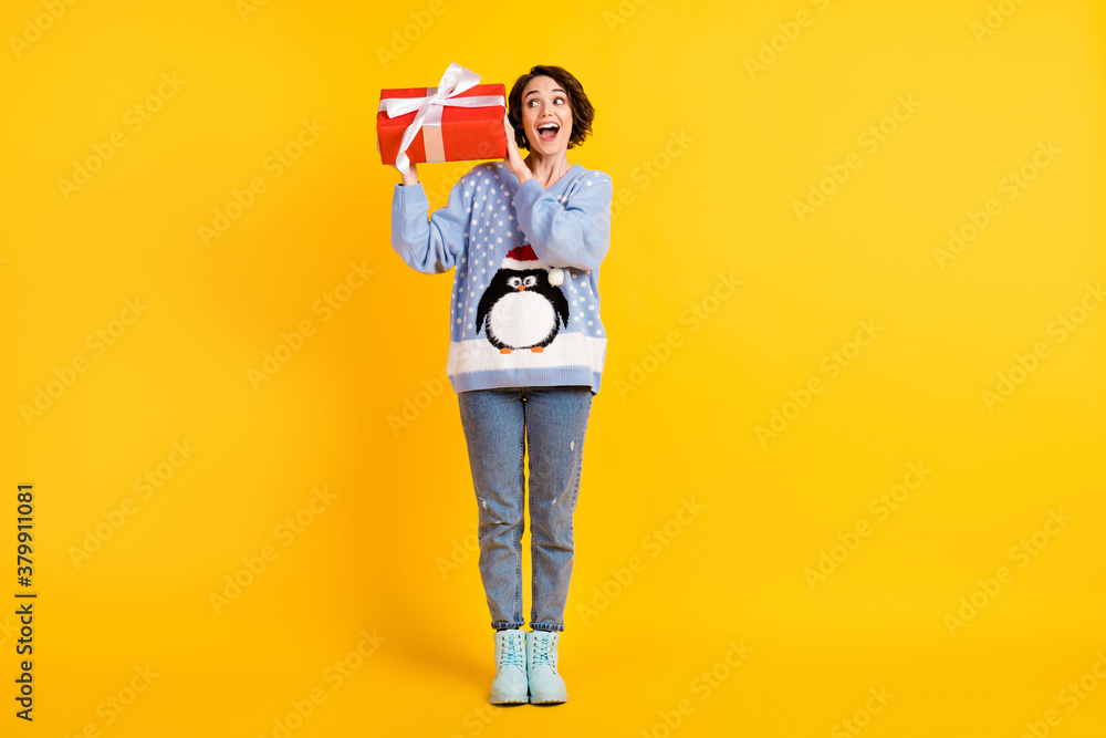 Full length photo of attractive tricky lady x-mas party hold newyear surprise big red giftbox guess what inside curious wear ugly ornament sweater jeans boots isolated yellow color background Full length photo of attractive tricky lady x-mas party hold newyear surprise big red giftbox guess what inside curious wear ugly ornament sweater jeans boots isolated yellow color background