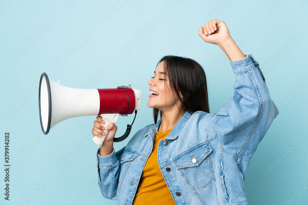 Teenager girl isolated on yellow background shouting through a megaphone to announce something in lateral position Teenager girl isolated on yellow background shouting through a megaphone to announce something in lateral position