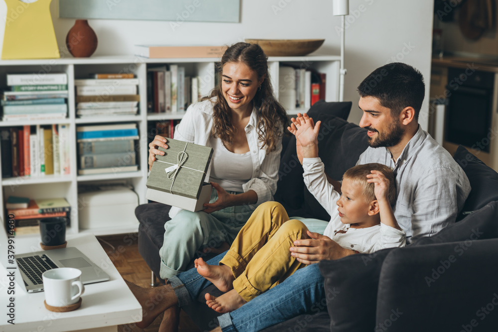 family sharing gifts and having video call on laptop computer, sitting on sofa at home family sharing gifts and having video call on laptop computer, sitting on sofa at home