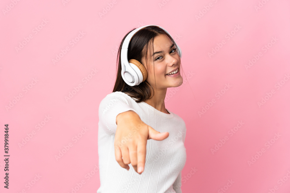 Obraz premium Teenager girl isolated on blue background listening music