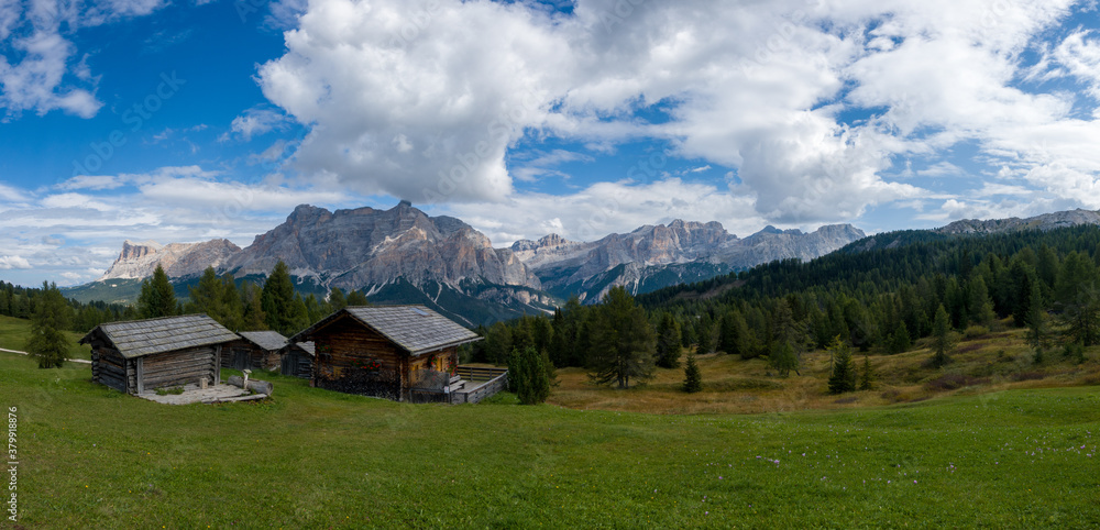 Hiking in the Dolomites - beautiful mountain panorama in the background and traditional huts in the foreground, South Tirol Italy