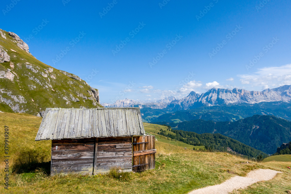 Hiking in the Dolomites - beautiful mountain panorama in the background and traditional huts in the foreground, South Tirol Italy