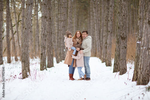 father and mother with their little daughters in the snowy winter forest. travel and recreation with children in winter. family walks in the fresh air during the new year holidays. © andrey