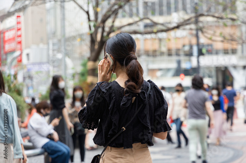 渋谷駅ハチ公口で電話をする女性の後ろ姿