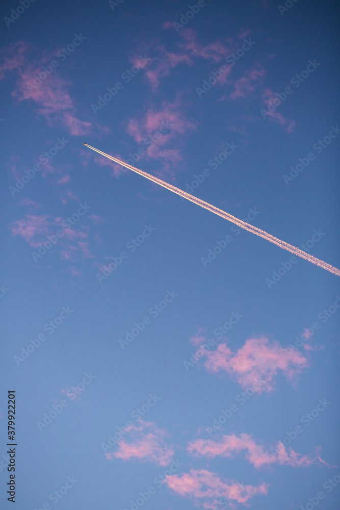 White contrail and tiny airplane against blue sky White contrail and tiny airplane against blue sky