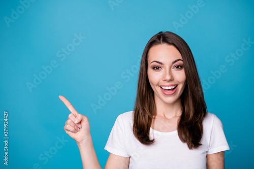 Closeup photo of attractive funny lady good mood directing fingers side up empty space presenting novelty banner sale discount prices wear casual white t-shirt isolated blue color background