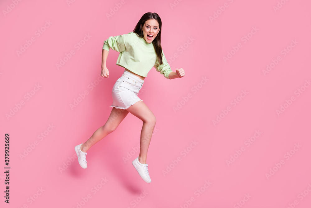 Full size profile side photo of surprised energetic girl hear incredible discounts news jump run fast wear green white stylish trendy sweater shoes isolated over pastel color background Full size profile side photo of surprised energetic girl hear incredible discounts news jump run fast wear green white stylish trendy sweater shoes isolated over pastel color background