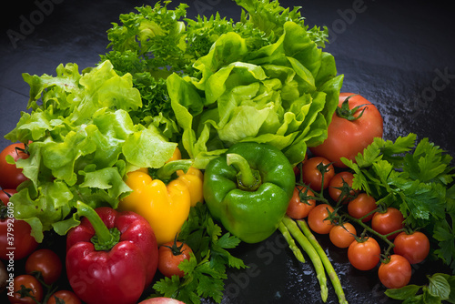 Set of fresh vegetables on black stone background. red yellow and green pepper  tomato  green oak  cos  Romaine  garlic  asparagus  mushroom and coriander with copy space.