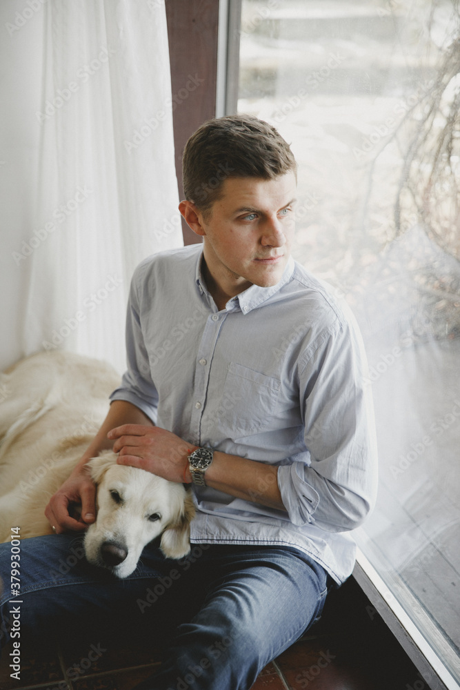 Man looking at window and stroking dog