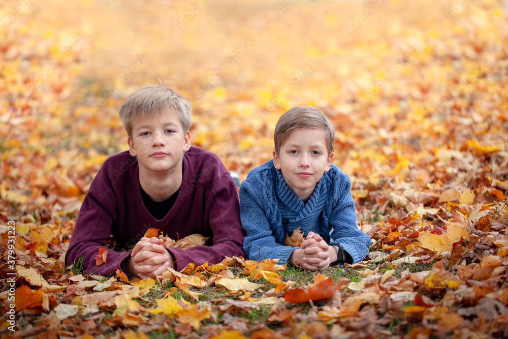 Two little brothers boys lying in autumn leaves. Happy siblings kids having fun in autumn forest Two little brothers boys lying in autumn leaves. Happy siblings kids having fun in autumn forest