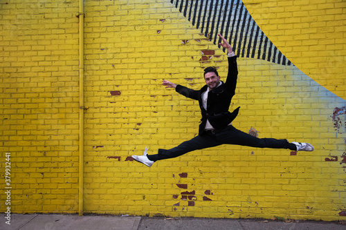 danseur en plein saut devant un mur de brique recouvert d un immense graffiti en milieu urbain 