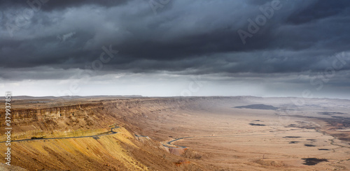 A road descending to the bottom of a mountainous desert canyon, panoramic view.