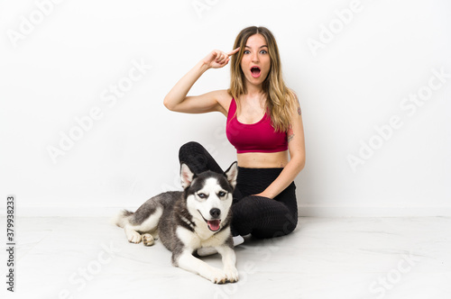 Young sport girl with her dog sitting on the floor intending to realizes the solution