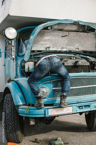 male mechanic repairing old truck in a funny way and showing his butt photo