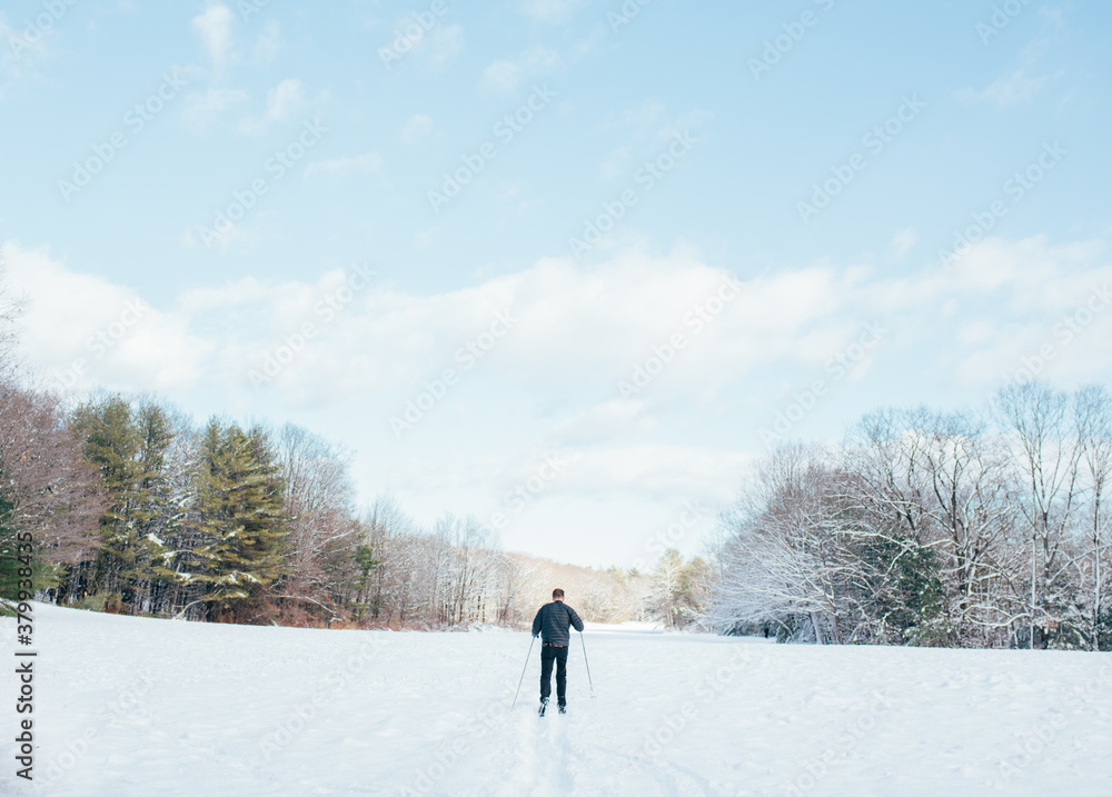 Man cross country skiing across a field with freshly fallen snow Man cross country skiing across a field with freshly fallen snow