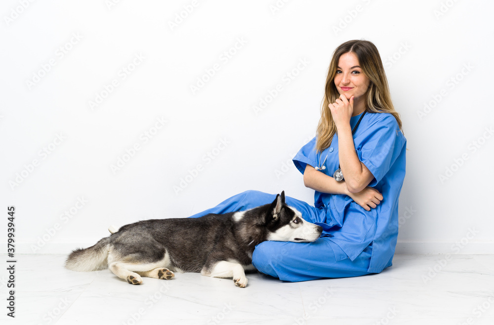 Veterinary doctor with Siberian Husky dog sitting on the floor laughing