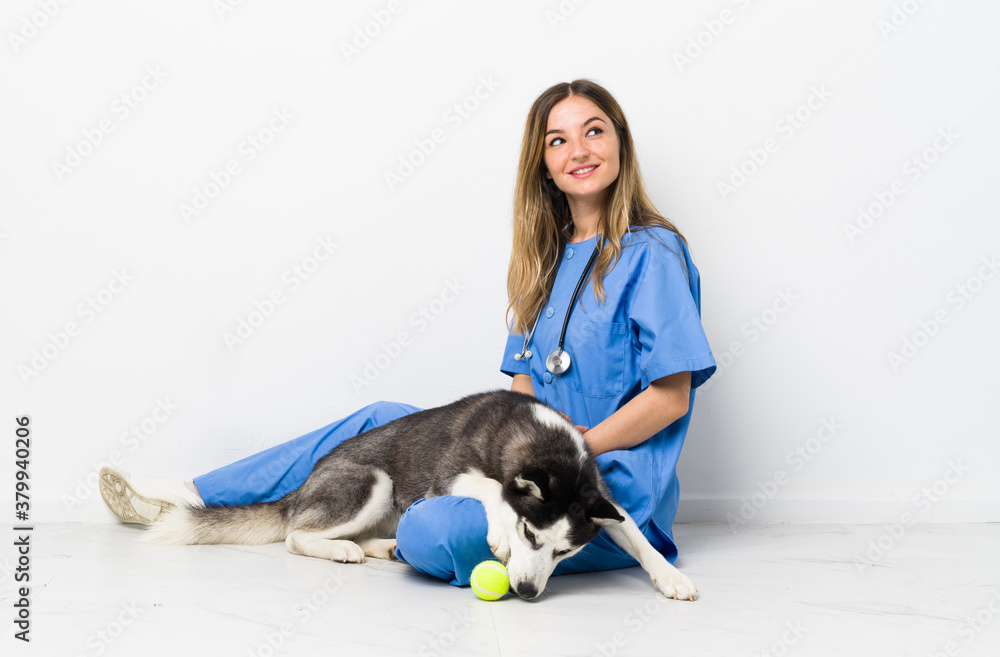 Veterinary doctor with Siberian Husky dog sitting on the floor laughing and looking up