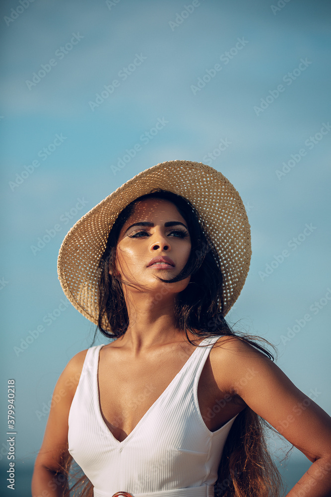 beautiful woman in white bathing suit on beach with hat