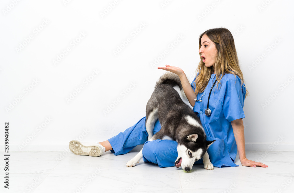 Veterinary doctor with Siberian Husky dog sitting on the floor holding copyspace imaginary on the palm Veterinary doctor with Siberian Husky dog sitting on the floor holding copyspace imaginary on the palm