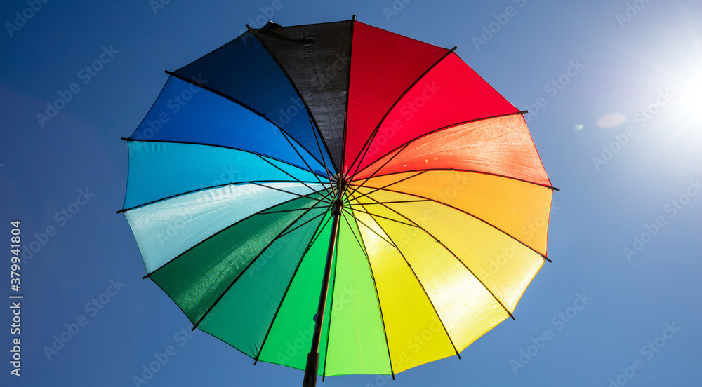 Umbrella rainbow colors on blue sky background