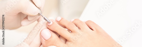 Beautiful salon procedure with pink pedicure on towel background. For decoration design. Healthcare. Woman body care. Spa treatment. White background. Nail machine polish. Medical photo
