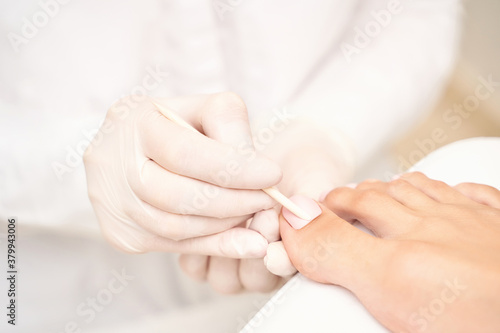 Beautiful salon procedure with pink pedicure on towel background. For decoration design. Healthcare. Woman body care. Spa treatment. White background. Nail polish. Apricot stick prepare