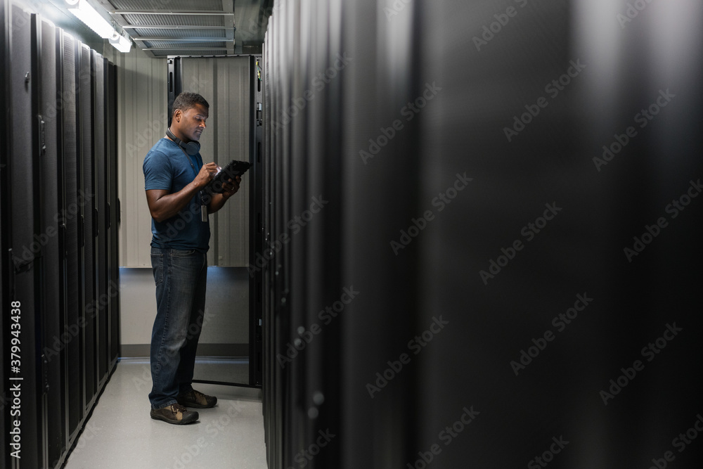 Server room technician looking at digital tablet Server room technician looking at digital tablet