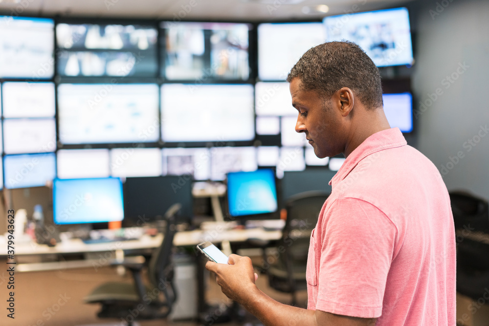 Technician looking at his cellphone in a server room monitoring Technician looking at his cellphone in a server room monitoring