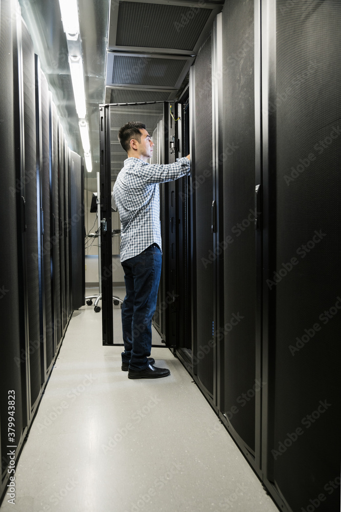 Vertical shot of technician working on a server in a cabinet in Vertical shot of technician working on a server in a cabinet in
