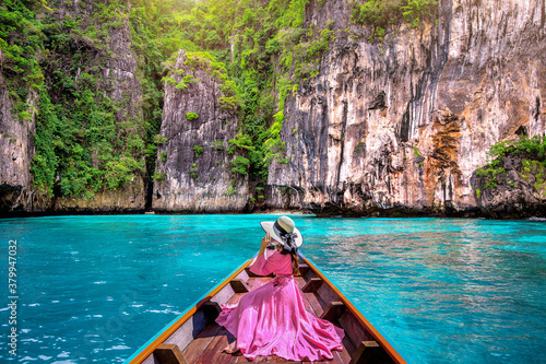 Fotografie, Obraz Beautiful girl sitting on the boat and looking to mountains in Phi phi island, Thailand