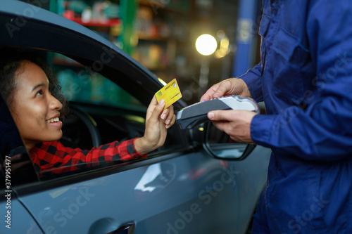 Female customer made a payment on the car by giving a credit card to the male mechanic in the garage.