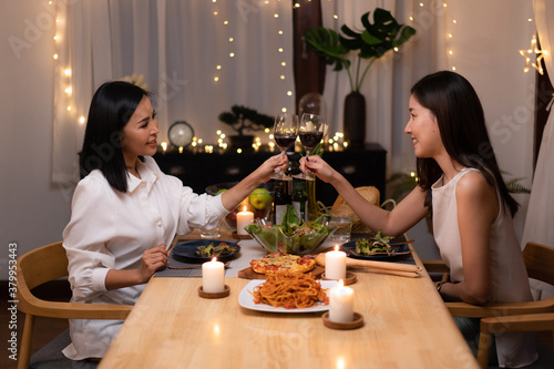 Asian young lesbian couple have a romantic, candlelit dinner in her home.
