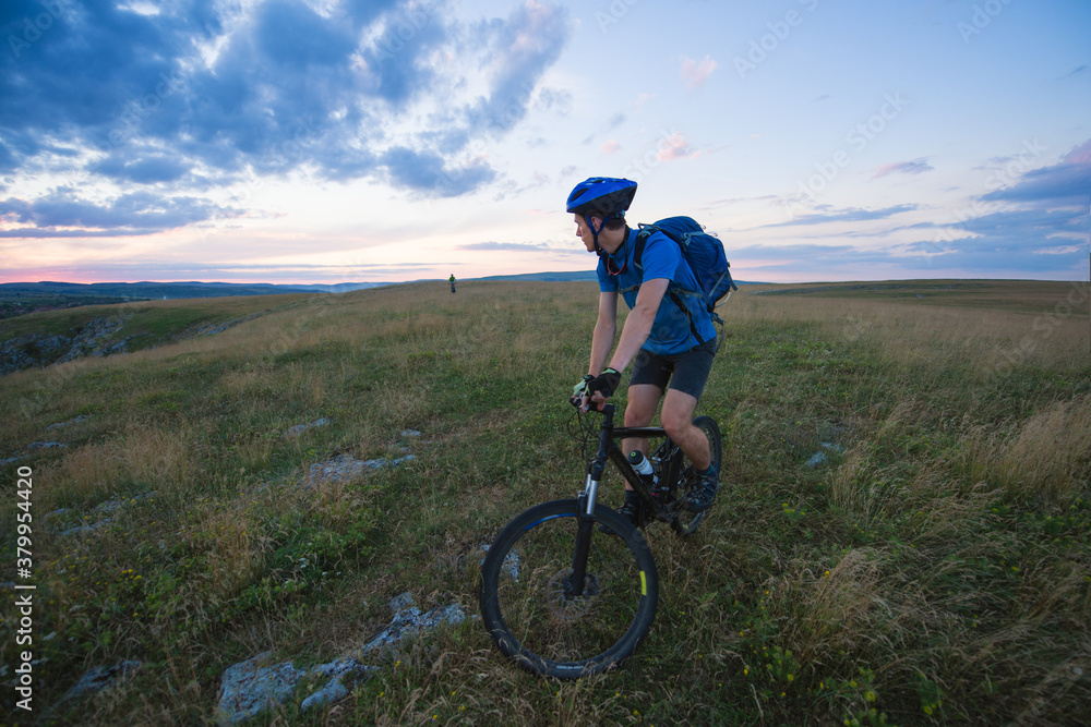 Young man on mountain bike crossing a green meadow Young man on mountain bike crossing a green meadow