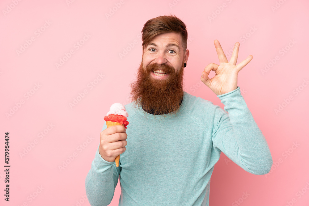 Redhead man with long beard holding a cornet ice cream over isolated pink background showing ok sign with fingers Redhead man with long beard holding a cornet ice cream over isolated pink background showing ok sign with fingers