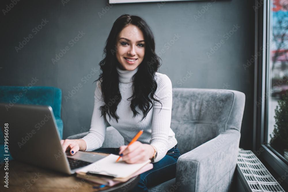 Positive woman with laptop taking notes in office Positive woman with laptop taking notes in office