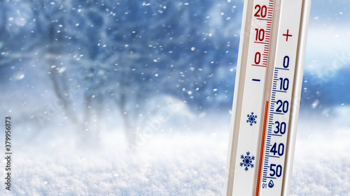 фотографія Thermometer on a background of winter forest shows 20 degrees below zero