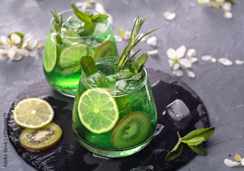 Non-alcoholic Mojito cocktail in a glass with syrup, fresh mint, lime and kiwi slices, sparkling water with ice. It has a citrus aroma and pleasant taste. Non-alcoholic Mojito cocktail in a glass with syrup, fresh mint, lime and kiwi slices, sparkling water with ice. It has a citrus aroma and pleasant taste.