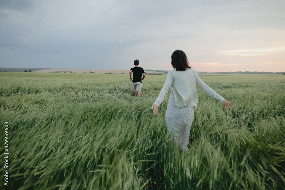 Back view of couple running across the field of wheat Back view of couple running across the field of wheat