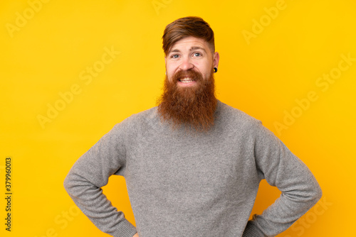 Redhead man with long beard over isolated yellow background angry