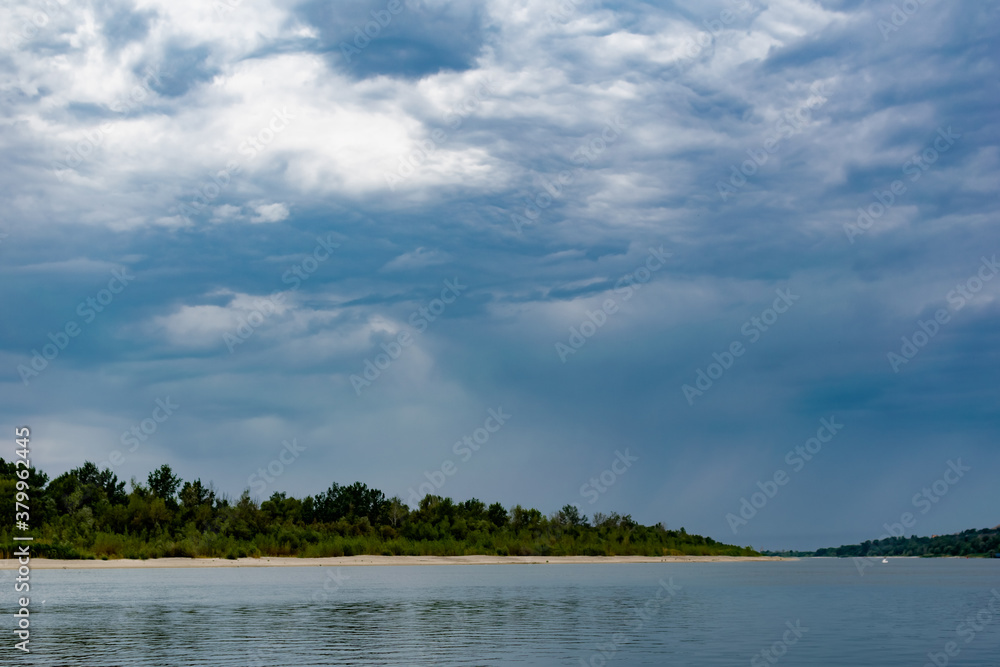 Simple landscape with the freshwater river don in the Rostov region. Warm season, summer, cloudy sky over the sandy beach and green vegetation.
